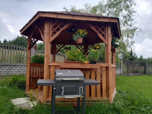 a wooden gazebo with a grill in a yard at RAMAR in Bodzentyn