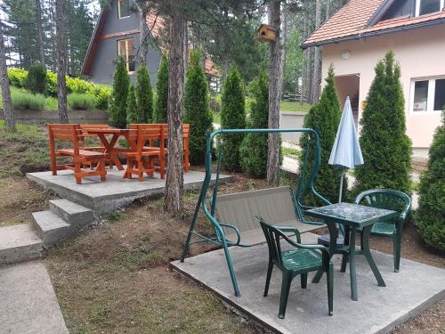 a patio with chairs and a table and an umbrella at Mountain House Tara Apartmani Nikolic in Kaludjerske Bare