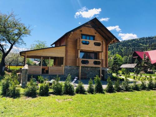 a log house with a garden in front of it at Айворі Хаус in Mykulychyn