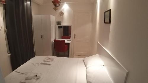 a white bedroom with a white bed and a red chair at Görkemli Hotel in Istanbul
