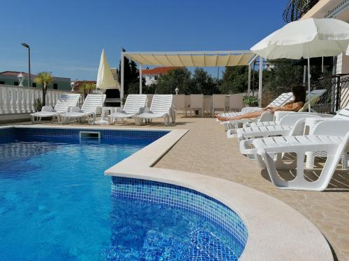 une femme assise sur des chaises à côté d'une piscine dans l'établissement Apartments Ćurić, à Trogir