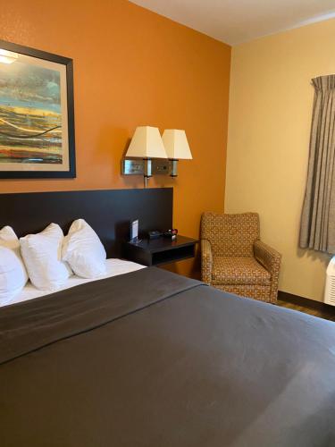 a hotel room with a bed and a chair at Suburban Studios Washington, PA in Washington