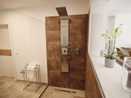 a bathroom with a shower with a wooden wall at SEE Moment Appartements ADULTS ONLY in St. Wolfgang