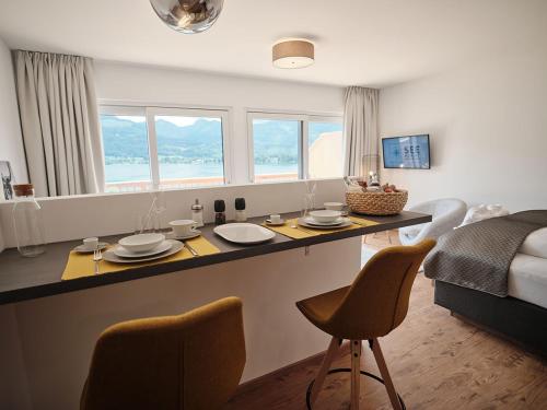 SEE Moment Appartements ADULTS ONLY في سانت ولفغانغ: مطبخ وغرفة معيشة مع طاولة وكراسي