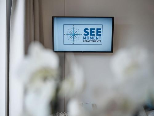 a television on a wall with aessenmovements sign on it at SEE Moment Appartements ADULTS ONLY in St. Wolfgang