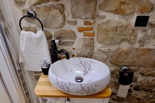 a white sink in a bathroom with a stone wall at La Corte di Kate-2 in Biograd na Moru