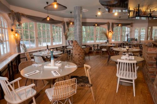 a restaurant with tables and chairs and windows at Seehotel Villago in Eggersdorf