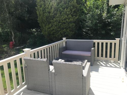a porch with a bench and two wicker chairs at Poppy at Oakdene Forest Park in Ringwood