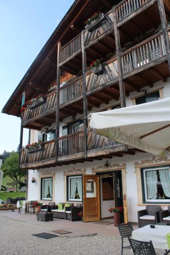 a large building with a balcony and tables and chairs at Rifugio Caltena in Fiera di Primiero