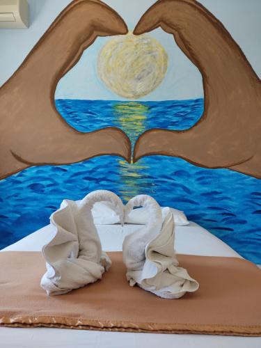 two swans laying on a bed with a painting at Amaranthos Skiathos View in Megali Ammos