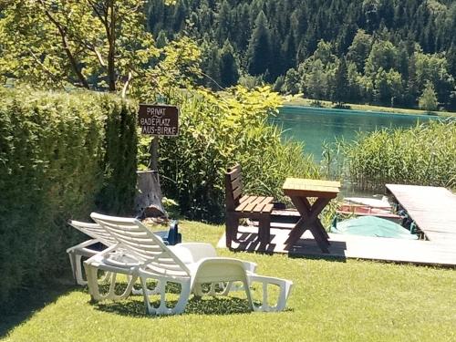 a group of chairs and a picnic table next to a pond at Haus Birke in Weissensee