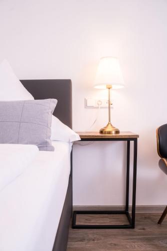 a bed with a table with a lamp on it at CityApartements FN2-FN4 KLIMATISIERT in Friedrichshafen