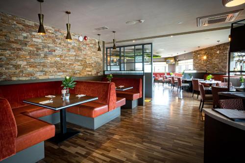 a restaurant with red seats and a brick wall at Greenhills Hotel Limerick in Limerick