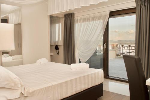 a white bedroom with a bed and a balcony at Hotel Boutique Castiglione del Lago in Castiglione del Lago