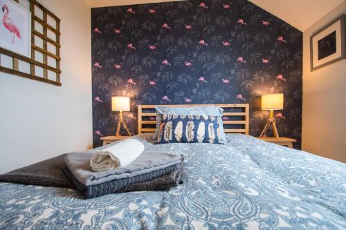 a bedroom with a blue bed with a black and pink wallpaper at Beautiful Three Bedroom home in Bundoran in Bundoran