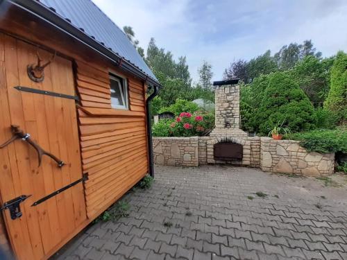 a wooden garage with a stone fireplace in a yard at IOMAN HAUS in Ikšķile