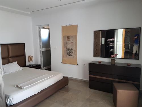 ein Schlafzimmer mit einem Bett, einer Kommode und einem TV in der Unterkunft Dar Doudi in Sousse