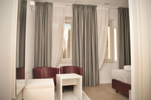 a bedroom with a bed and two chairs and a table at Hotel Boutique Castiglione del Lago in Castiglione del Lago