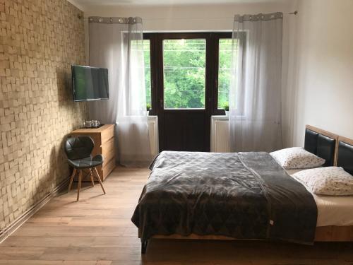 a bedroom with a bed and a window and a chair at Loft Wisla Houses in Wisła
