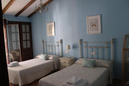 2 camas en una habitación con paredes azules en Casa Rural Leonor con piscina privada, en Casar de Palomero