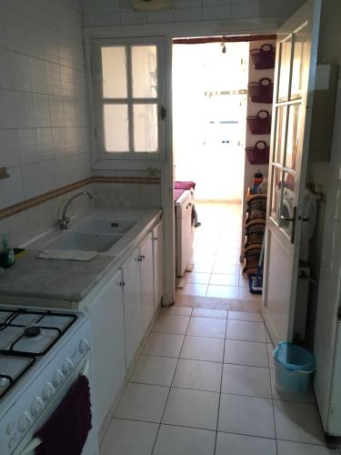 a white kitchen with a sink and a stove at Belaire host appartment in Boumhel El Bassatine