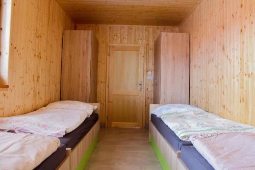 two beds in a room with wooden walls at Chaty U Cvrků in Orlík