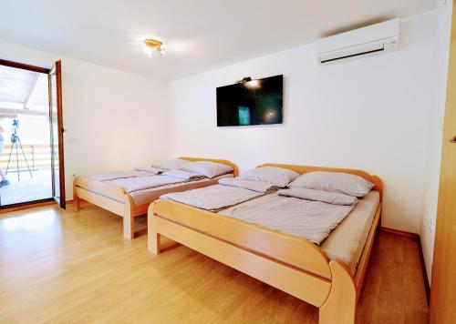 two beds in a room with a tv on the wall at Small wooden houses and Apartments Zgornja Dobrava in Radovljica