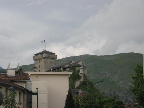 a castle with a flag on top of a building at Hôtel Acropolis - Lourdes in Lourdes
