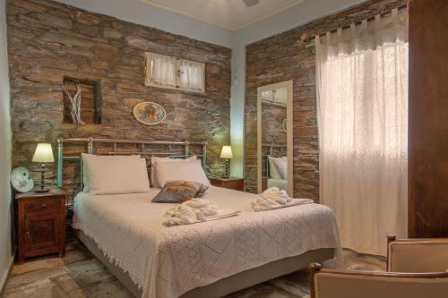 a bedroom with a bed and a stone wall at Kalimera Andros in Andros