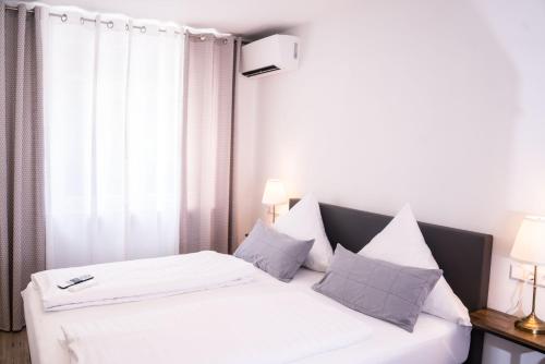 a bedroom with a bed with white sheets and pillows at CityApartements FN2-FN4 KLIMATISIERT in Friedrichshafen