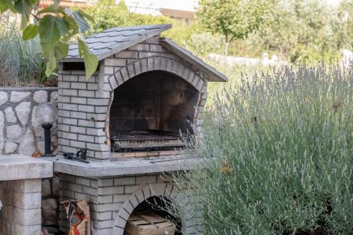a stone pizza oven in a garden with grass at Paradise Apartments in Lopar