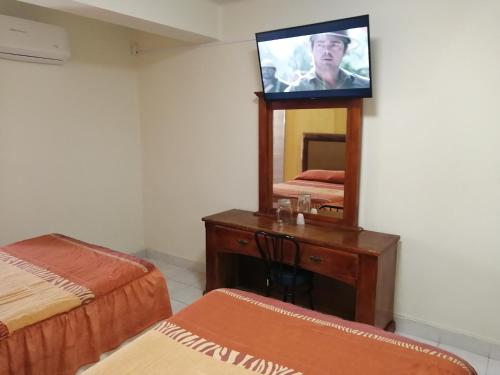 een kamer met 2 bedden en een televisie op een spiegel bij HOTEL BAEZA in Delicias