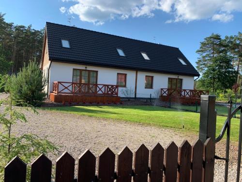 a white house with a black roof and a fence at Nad Wiartlem in Wiartel