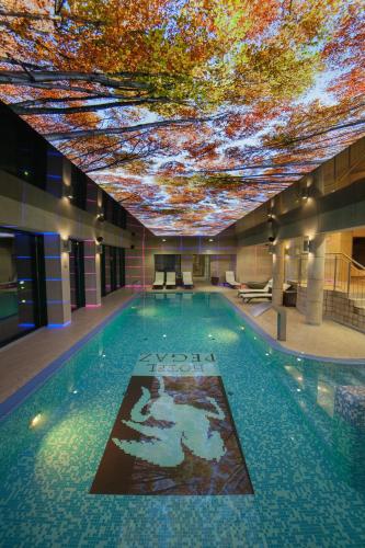 a large swimming pool with a ceiling covered in trees at Hotel Pegaz in Krynica Zdrój