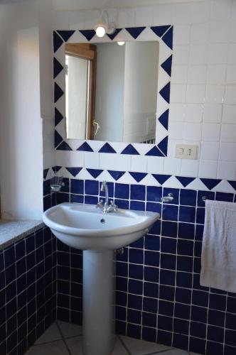 a blue tiled bathroom with a sink and a mirror at La Maddalena Apartment in La Maddalena