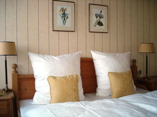 ein Bett mit weißen Kissen und zwei Bildern an der Wand in der Unterkunft Bayrischer Hof Wohlfühl - Hotel Saarbrücken in Saarbrücken