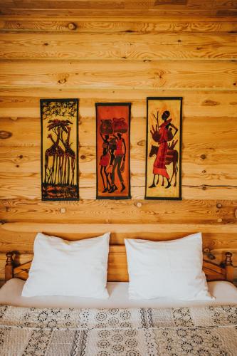 a wooden wall with four pictures above a bed at Guest House Baltās Dūjas in Saulkrasti