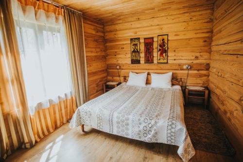 a bedroom with a bed in a log cabin at Guest House Baltās Dūjas in Saulkrasti