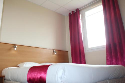 a bedroom with two beds and a window with red curtains at Hotel Le Saint Aubin in Gournay-en-Bray