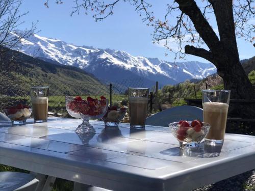 a table with drinks and bowls of fruit on it with a mountain at Roza's guest house in Mestia