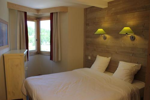 a bedroom with a bed with two lamps on the wall at Résidence Christiana 109 Clés Blanches Courchevel in Courchevel
