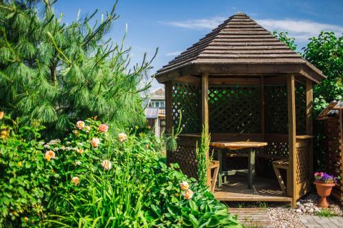 a wooden gazebo with a table in a garden at Guest House Baltās Dūjas in Saulkrasti