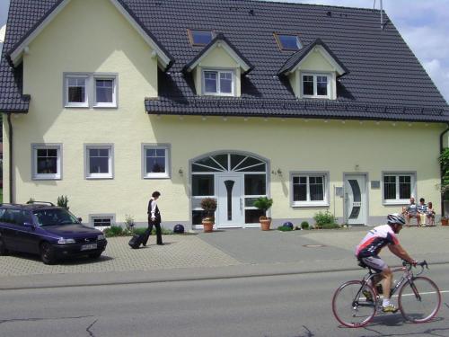 a person riding a bike in front of a house at Kurpension Meßmer in Tengen