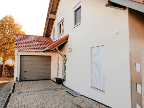 a white house with a garage with a door at Wohlfühl-Apartment Sinsheim, Nähe Therme und Museum in Sinsheim