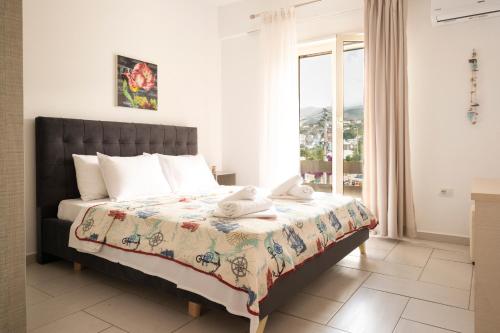 een slaapkamer met een bed en een groot raam bij Sea Apartments Himare in Himare