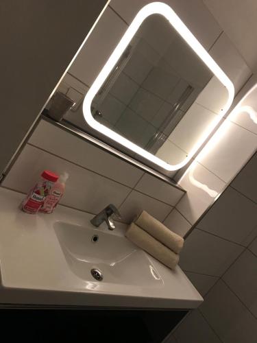 een badkamer met een wastafel, een spiegel en een licht bij Dream Apartment Wiesbaden City Balkon RHEIN MAIN CONGRESS CENTER in Wiesbaden