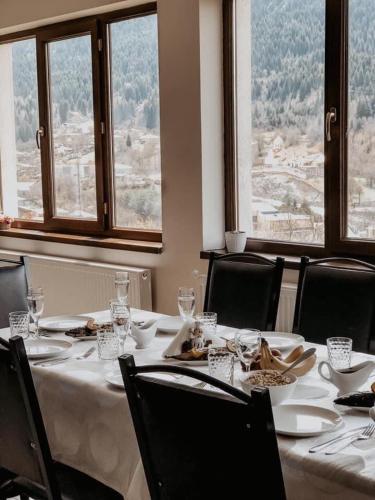 a dining room with a table and chairs and windows at Roza's guest house in Mestia