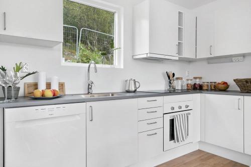 a white kitchen with white cabinets and a window at Hällestrand Village in Strömstad