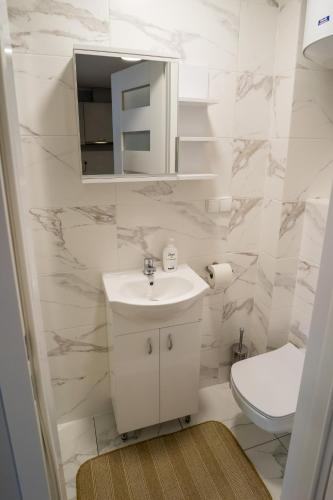 a white bathroom with a sink and a toilet at APARTAMENTY CENTRUM in Braniewo