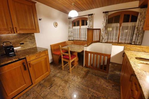 a kitchen with wooden cabinets and a table and chairs at Bezauberndes Haus für erholsame Ferien im Puschlav in Campascio